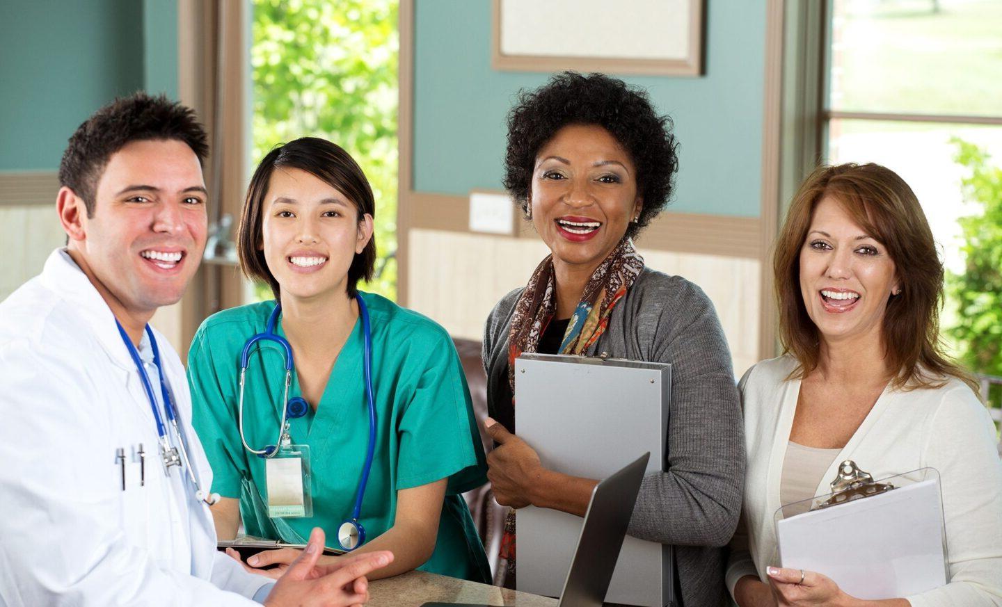 Community health workers with clipboards at desk with a doctor and a nurse